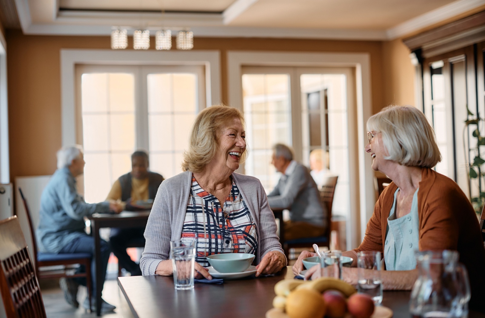 Two women sitting for lunch and laughing together.