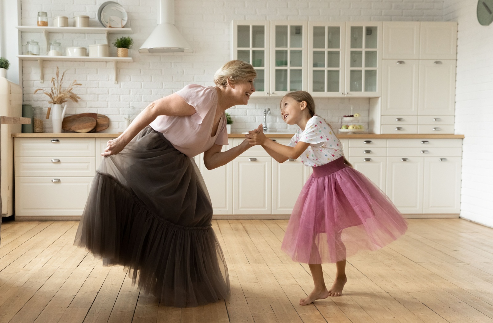 A grandparent happily dances with their grandchild.