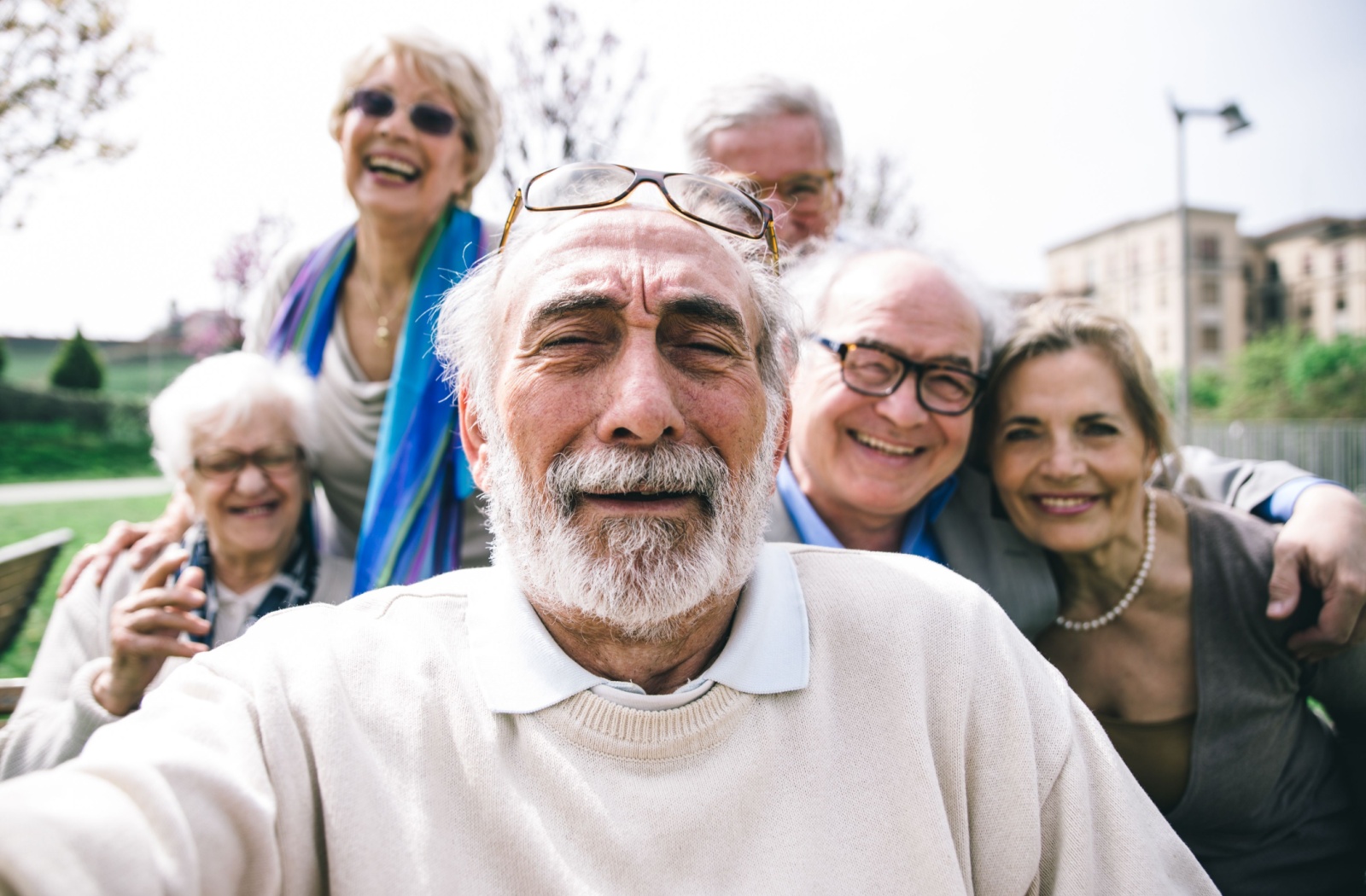 A senior with glasses on resting their head takes a picture of themselves and a group of friends while on an outing.