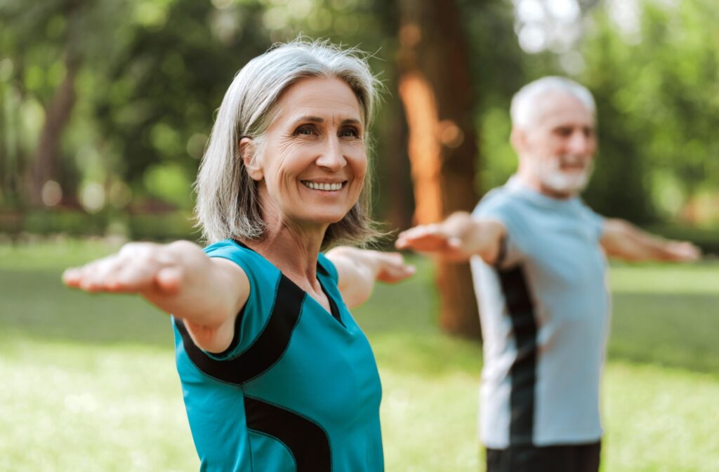 Two seniors exercise together in the park.