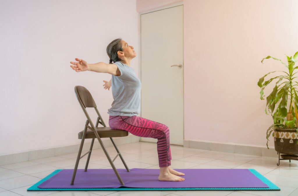 Someone sits on a chair and does a chest opening yoga pose.