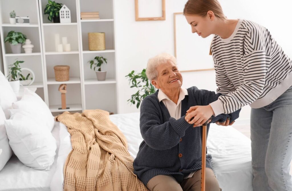 A young adult helps their grandparent out of bed, showcasing one way families help take care of their older loved ones