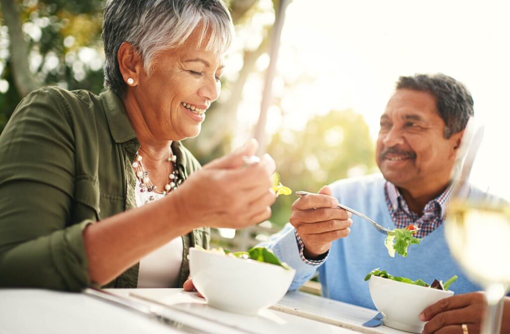 A senior couple enjoys a healthy salad full of nuts and fruits that promote brain health for an outdoor lunch